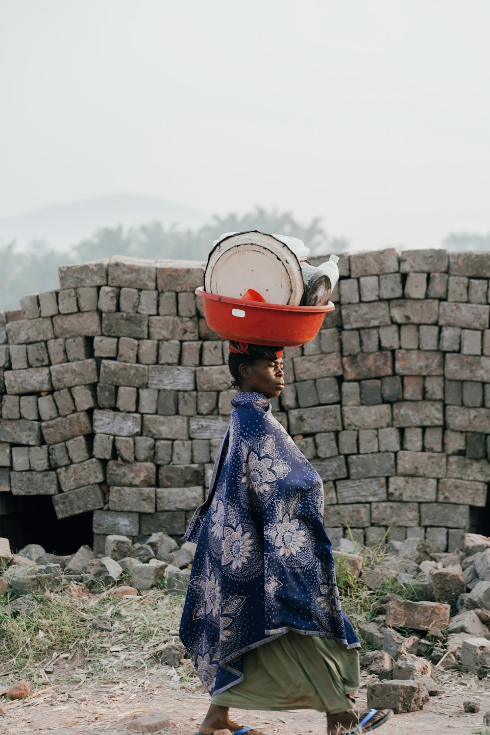 woman in blue and white floral dress wearing red hat standing near gray concrete wall during