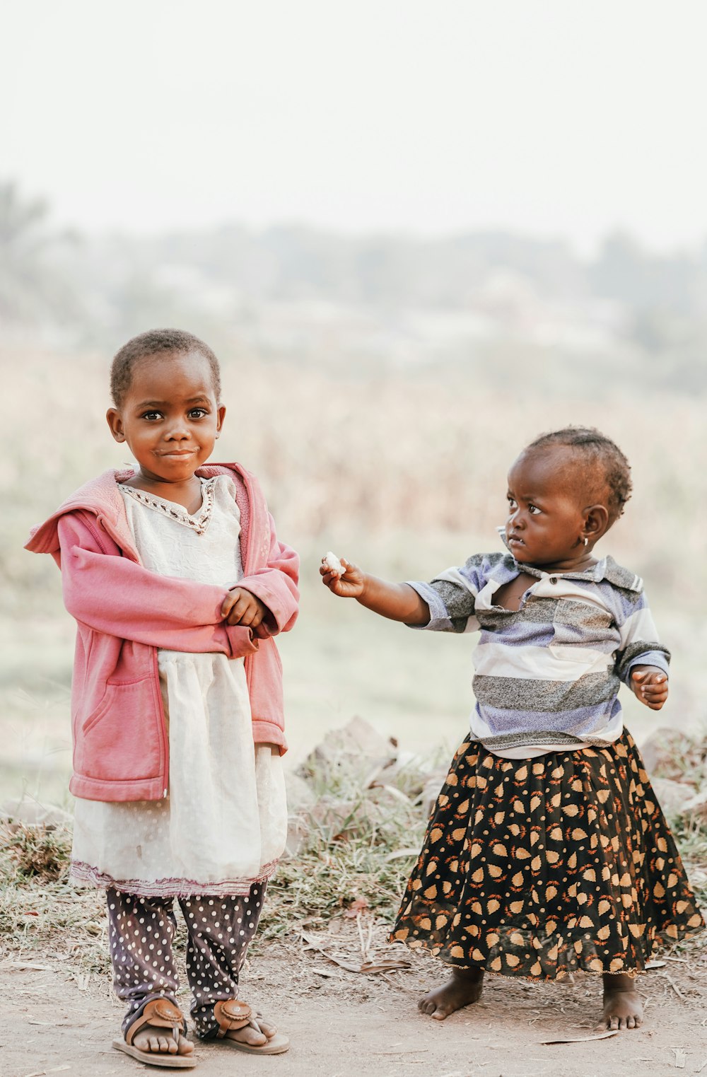 girl in black and white dress holding girl in pink cardigan during daytime