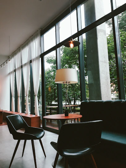 A cozy, modern serviced apartment with soft green accents and sunlight streaming through large windows.