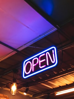 A vibrant neon open sign glowing above a stylish home bar setup in warm tones.