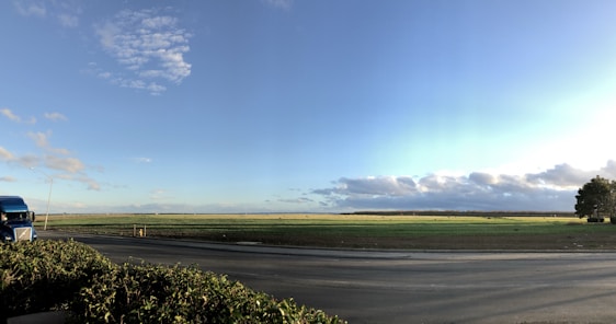 A fleet of trucks transporting agricultural goods through lush green fields under a clear sky.