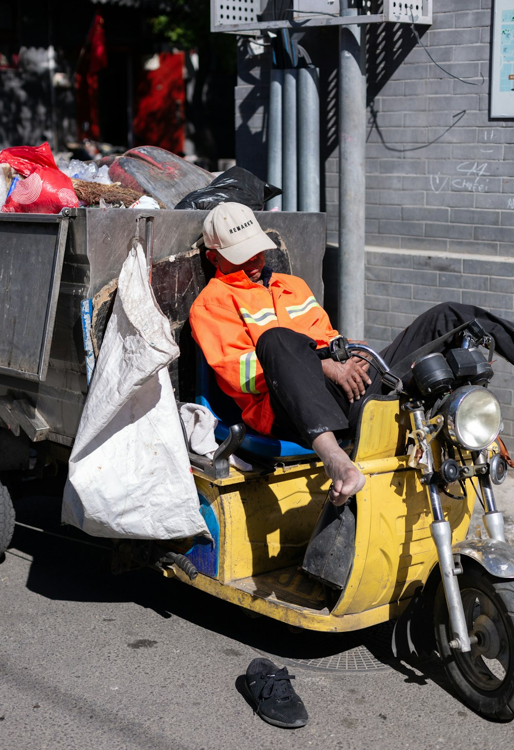 昼間、黄色いバイクに座るオレンジと白のジャケットを着た男性