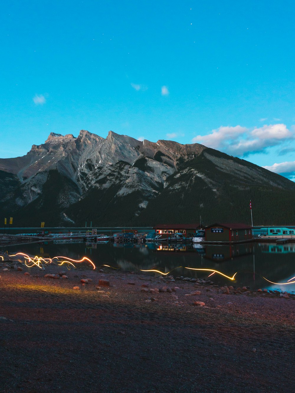 brown wooden dock near mountain under blue sky during daytime