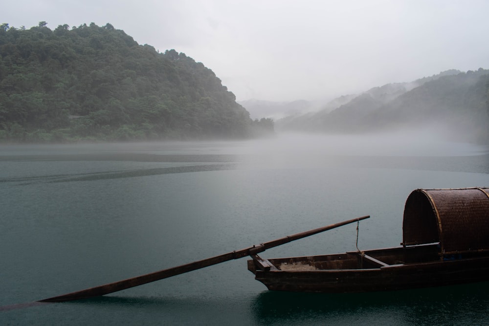 brown boat on calm water near green mountain during daytime