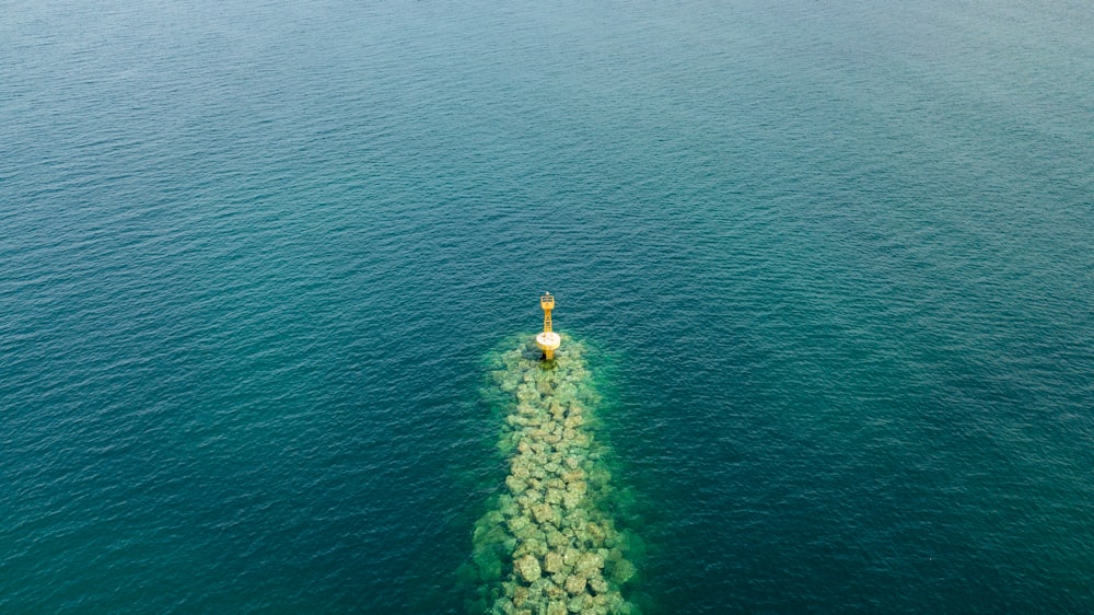 person in yellow jacket and yellow pants standing on rock in the middle of the sea