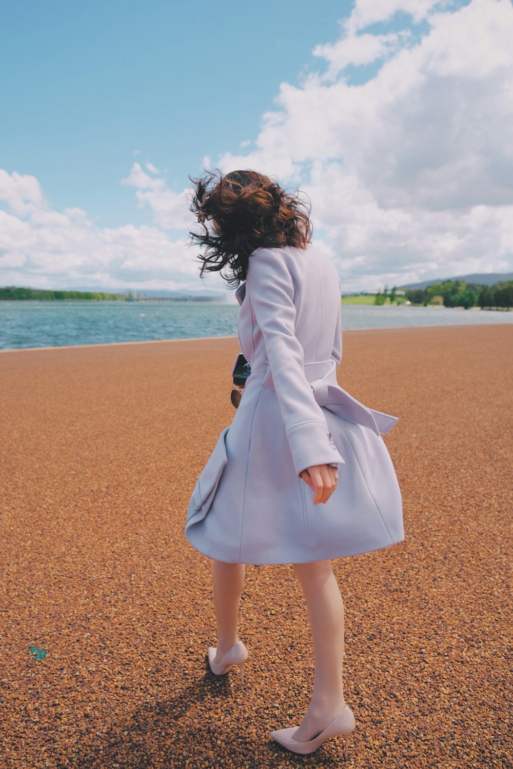 woman in white long sleeve dress standing on brown sand near body of water during daytime