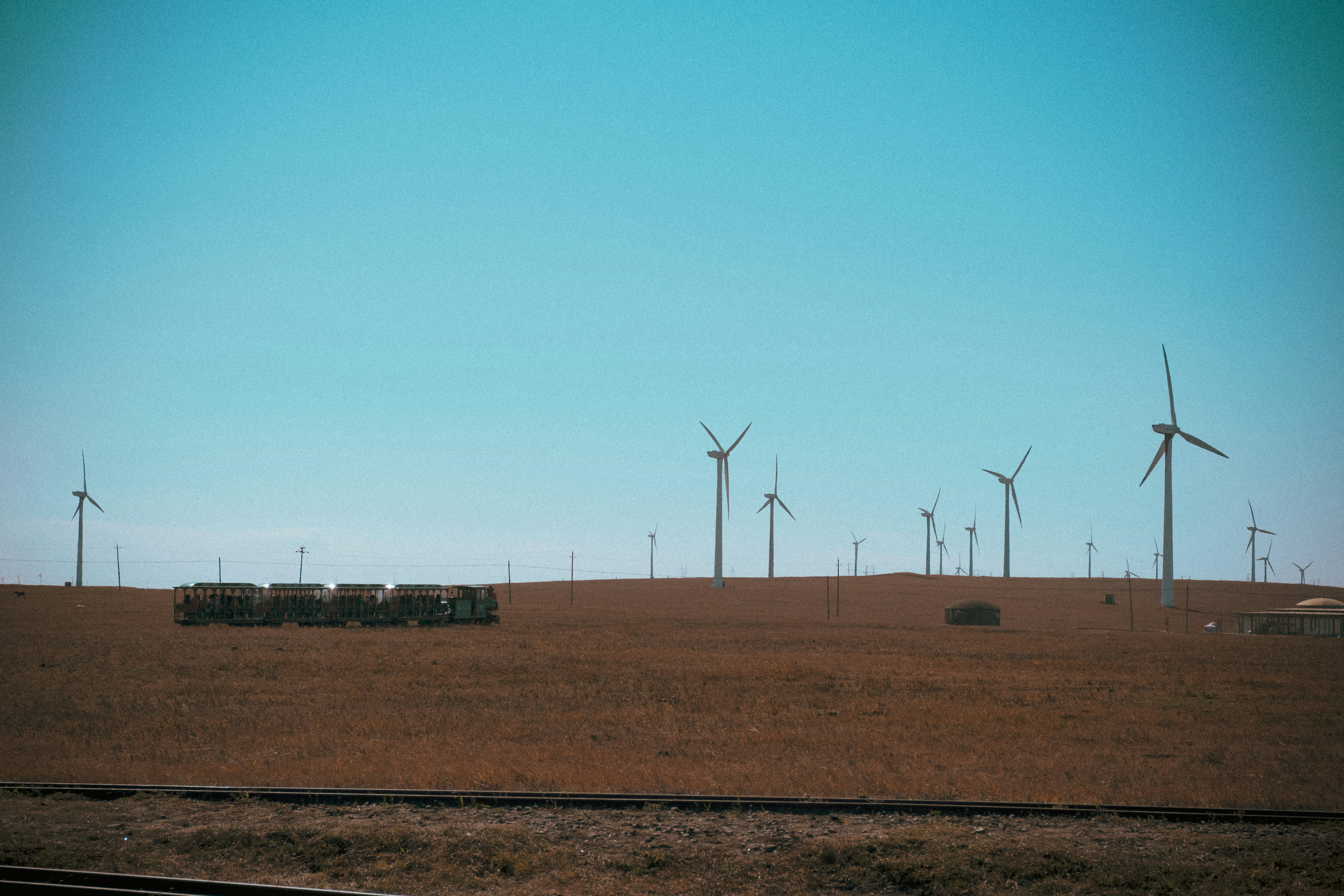 wind turbines on brown field under blue sky during daytime