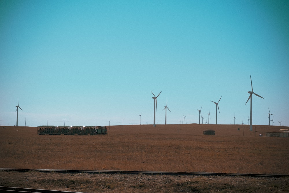 wind turbines on brown field under blue sky during daytime