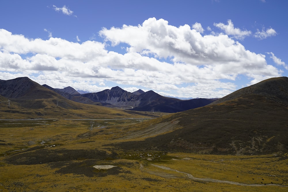 green and brown mountains under white clouds and blue sky during daytime