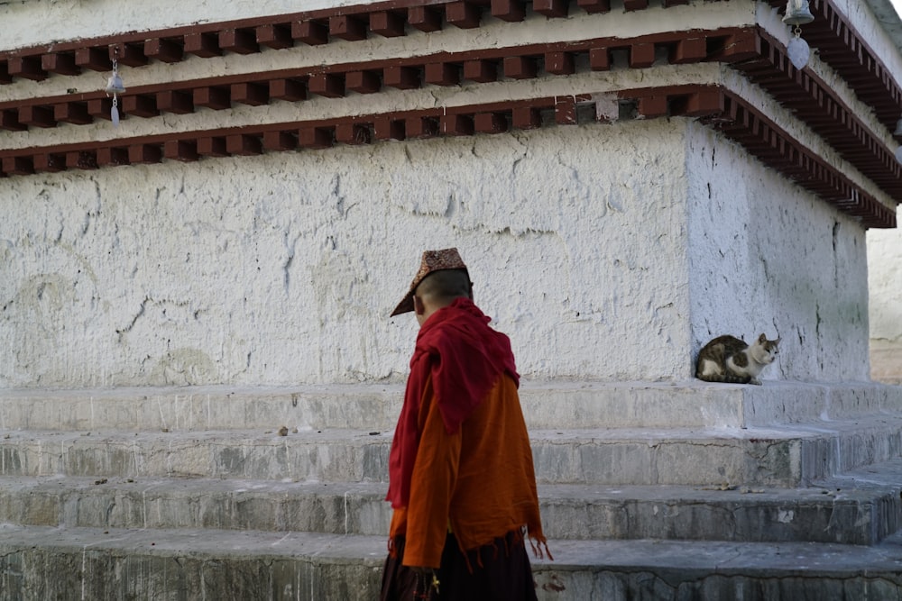 man in red coat standing near white wall