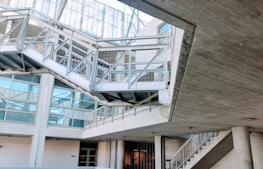 An industrial-looking architectural structure with metal beams and walkways. The design incorporates modern elements with glass windows and concrete walls. The building has various levels connected by metal stairs and pathways, creating an intricate, geometric pattern.