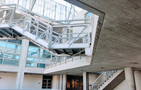 An industrial-looking architectural structure with metal beams and walkways. The design incorporates modern elements with glass windows and concrete walls. The building has various levels connected by metal stairs and pathways, creating an intricate, geometric pattern.