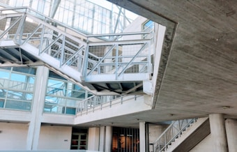 An industrial-looking architectural structure with metal beams and walkways. The design incorporates modern elements with glass windows and concrete walls. The building has various levels connected by metal stairs and pathways, creating an intricate, geometric pattern.