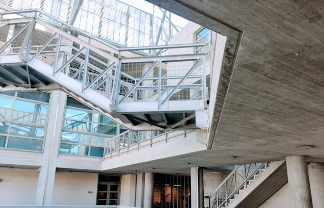 An industrial-looking architectural structure with metal beams and walkways. The design incorporates modern elements with glass windows and concrete walls. The building has various levels connected by metal stairs and pathways, creating an intricate, geometric pattern.
