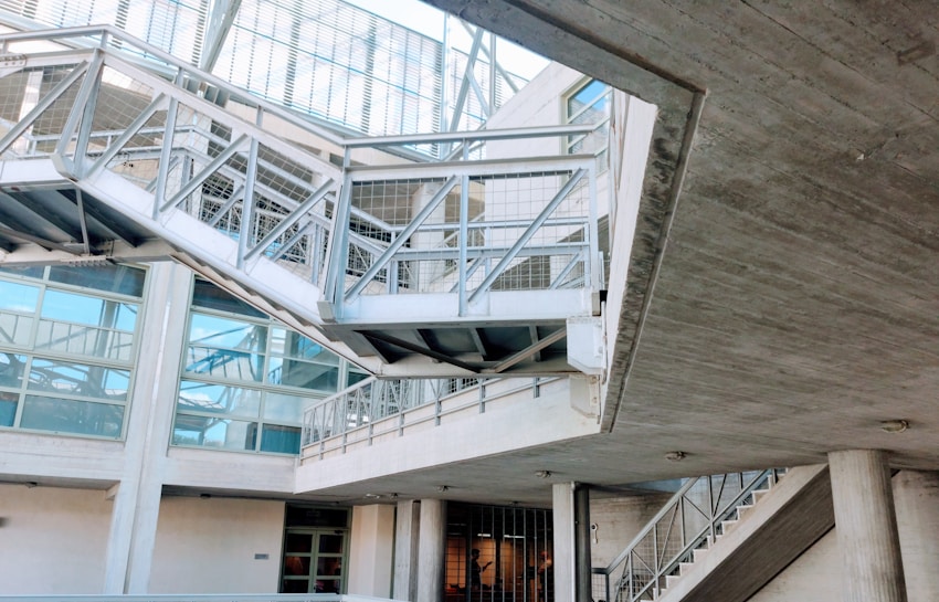 An industrial-looking architectural structure with metal beams and walkways. The design incorporates modern elements with glass windows and concrete walls. The building has various levels connected by metal stairs and pathways, creating an intricate, geometric pattern.