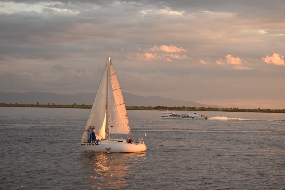 white sail boat on sea under cloudy sky during daytime