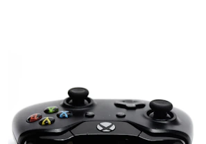 A black video game controller featuring brightly colored buttons on a white background. The directional pad and thumbsticks are prominent, indicating a focus on gaming functionality.