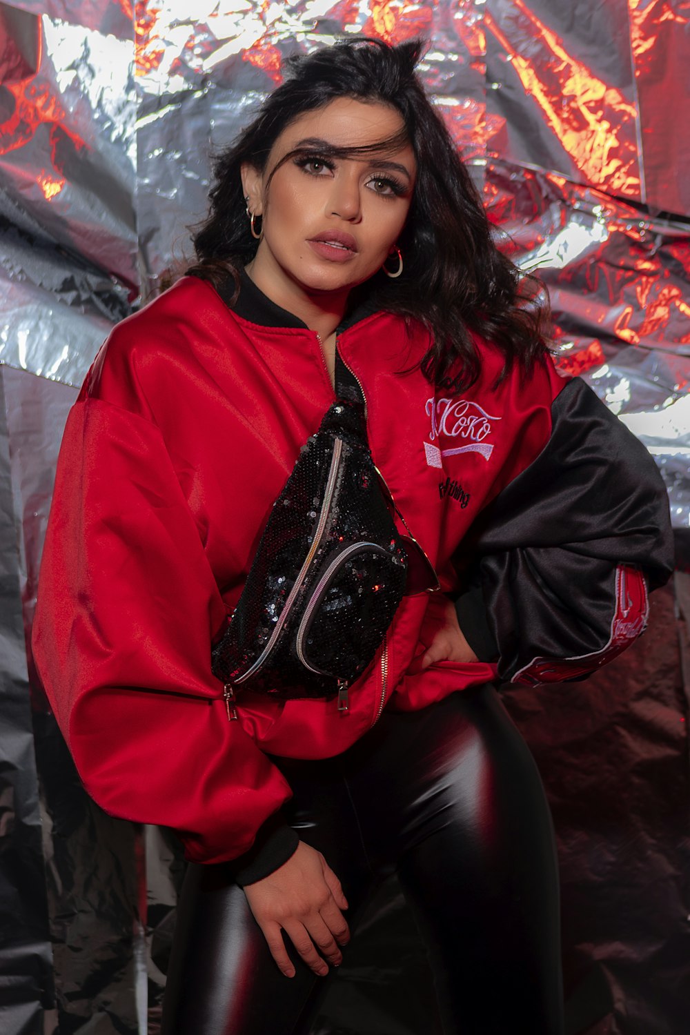 Femme en veste rouge assise sur un canapé en cuir noir