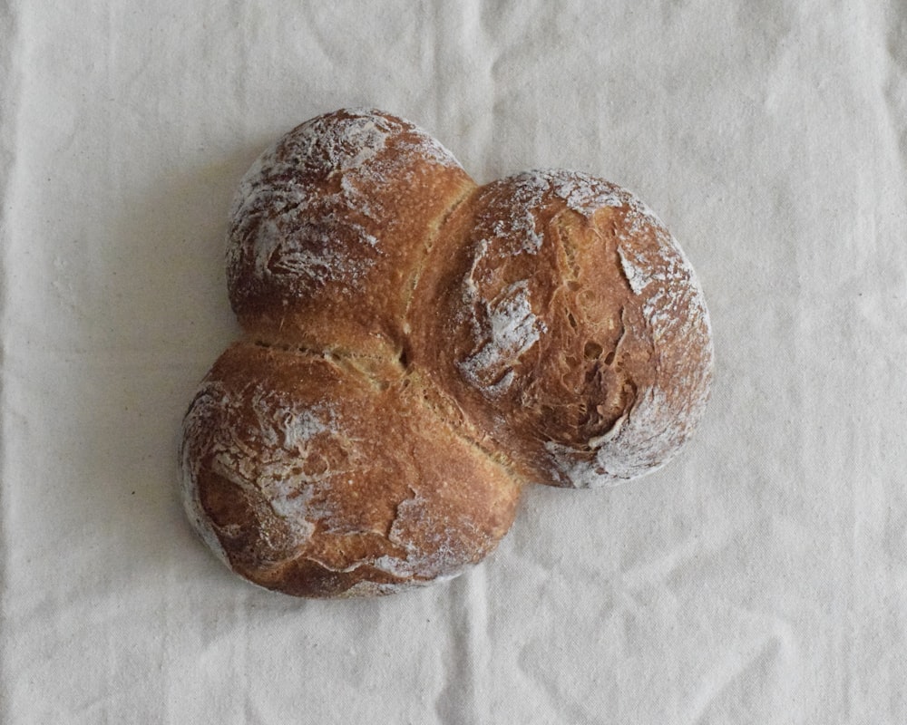 two brown breads on white textile