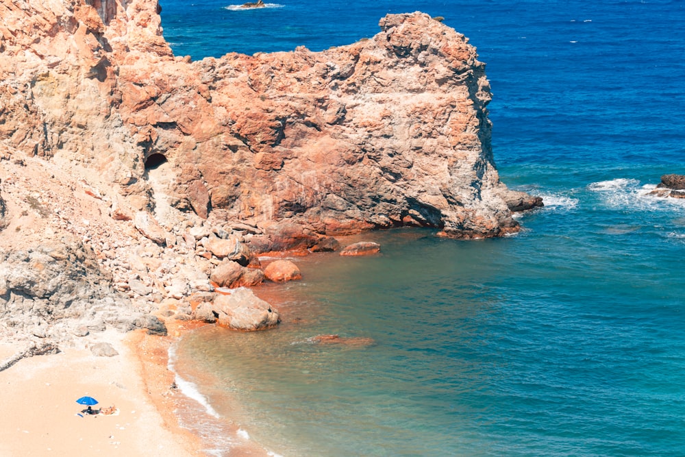 brown rock formation beside body of water during daytime