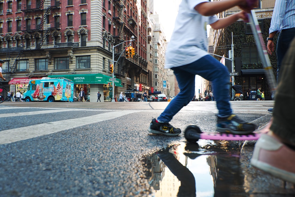 man in white t-shirt and blue denim jeans jumping on wet road during daytime