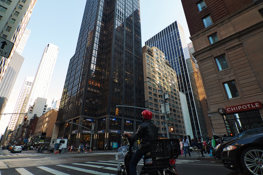 man in black jacket and black pants riding on black motorcycle on road during daytime on his way to pay broker's fee in NYC