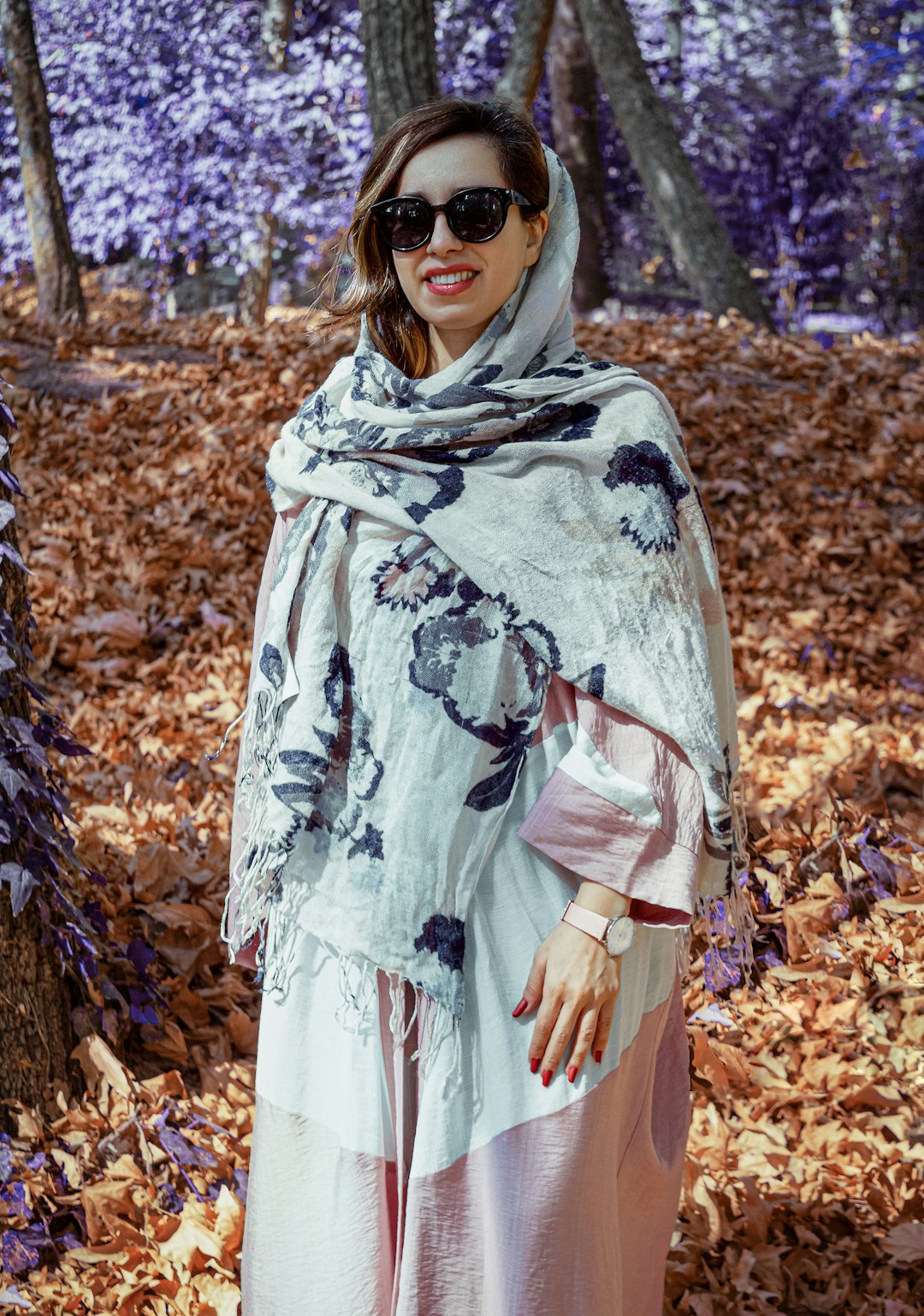 woman in white and green floral hijab standing on dried leaves