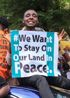 man in orange shirt holding blue and white happy birthday signage
