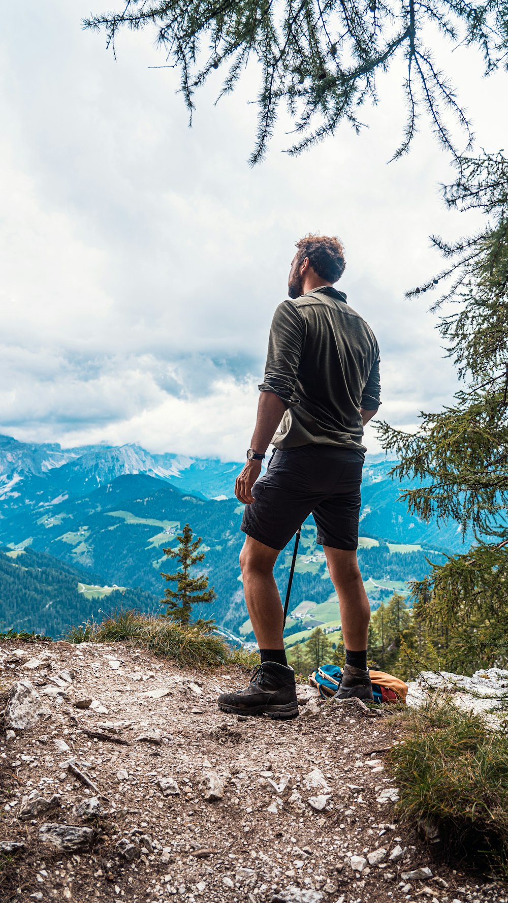 Uomo in maglietta grigia e pantaloncini neri in piedi sull'erba verde durante il giorno