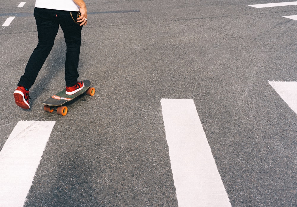 man in white shirt and blue denim jeans standing on brown skateboard during daytime