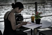 woman in black tank top writing on white paper