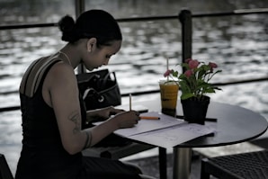 woman in black tank top writing on white paper