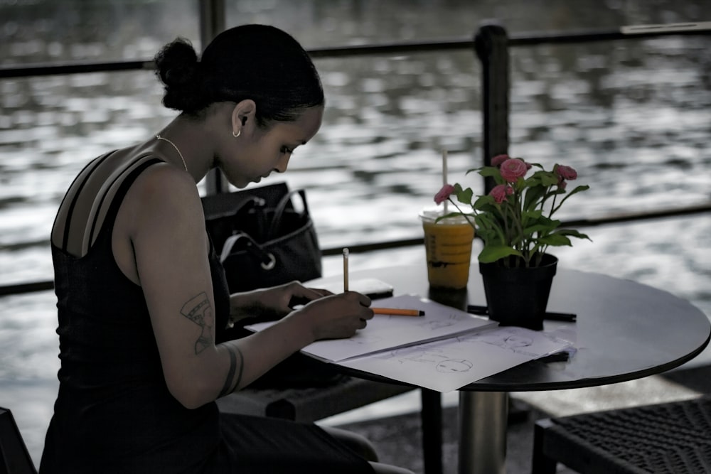 Femme en débardeur noir écrivant sur papier blanc