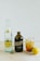 A product display on a light wooden surface featuring a bottle of Topo Chico mineral water, a dark brown bottle of Stumptown cold brew coffee, and a glass filled with iced tea and lemon slices. A lemon sits nearby next to one of the bottle caps.