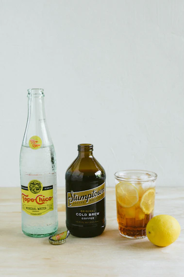 A beautifully arranged display of Xeque Mate beverages in colorful bottles on a rustic wooden table.