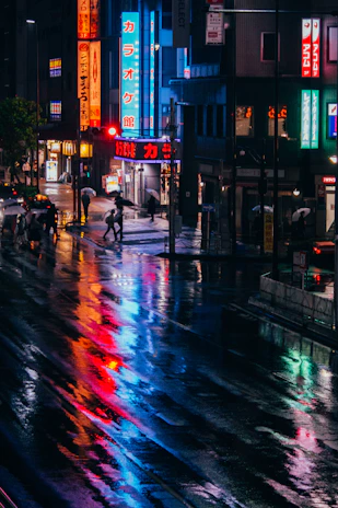 A cinematic still of a rainy city street at night, illuminated by neon signs reflecting on wet pavement.
