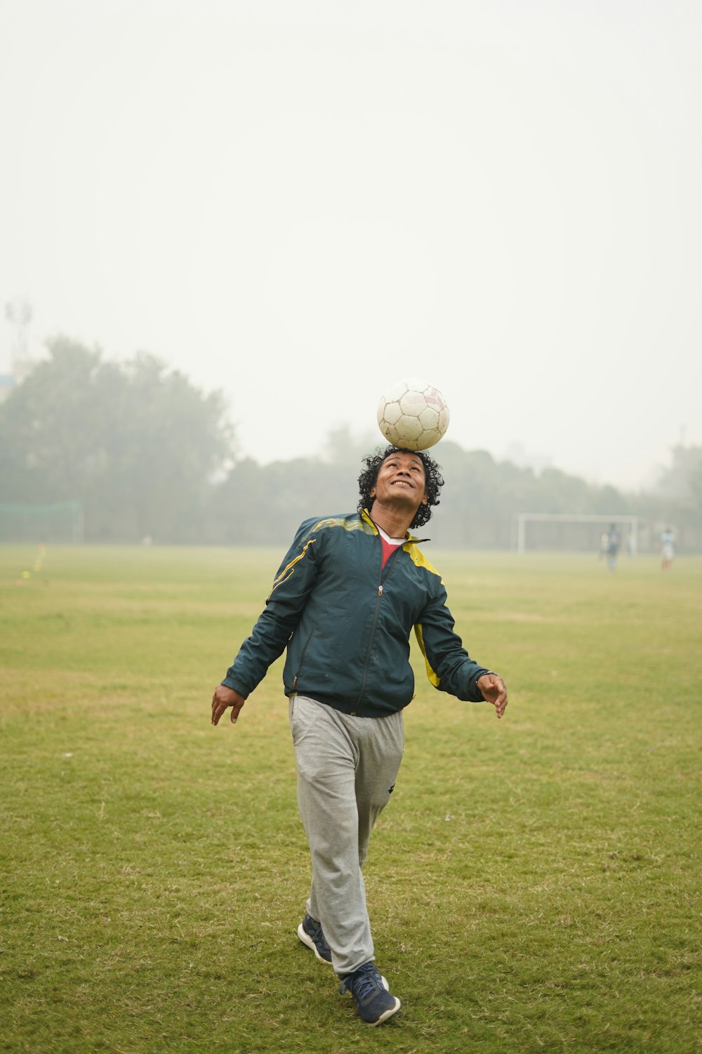 man in blue jacket and white pants holding white ball