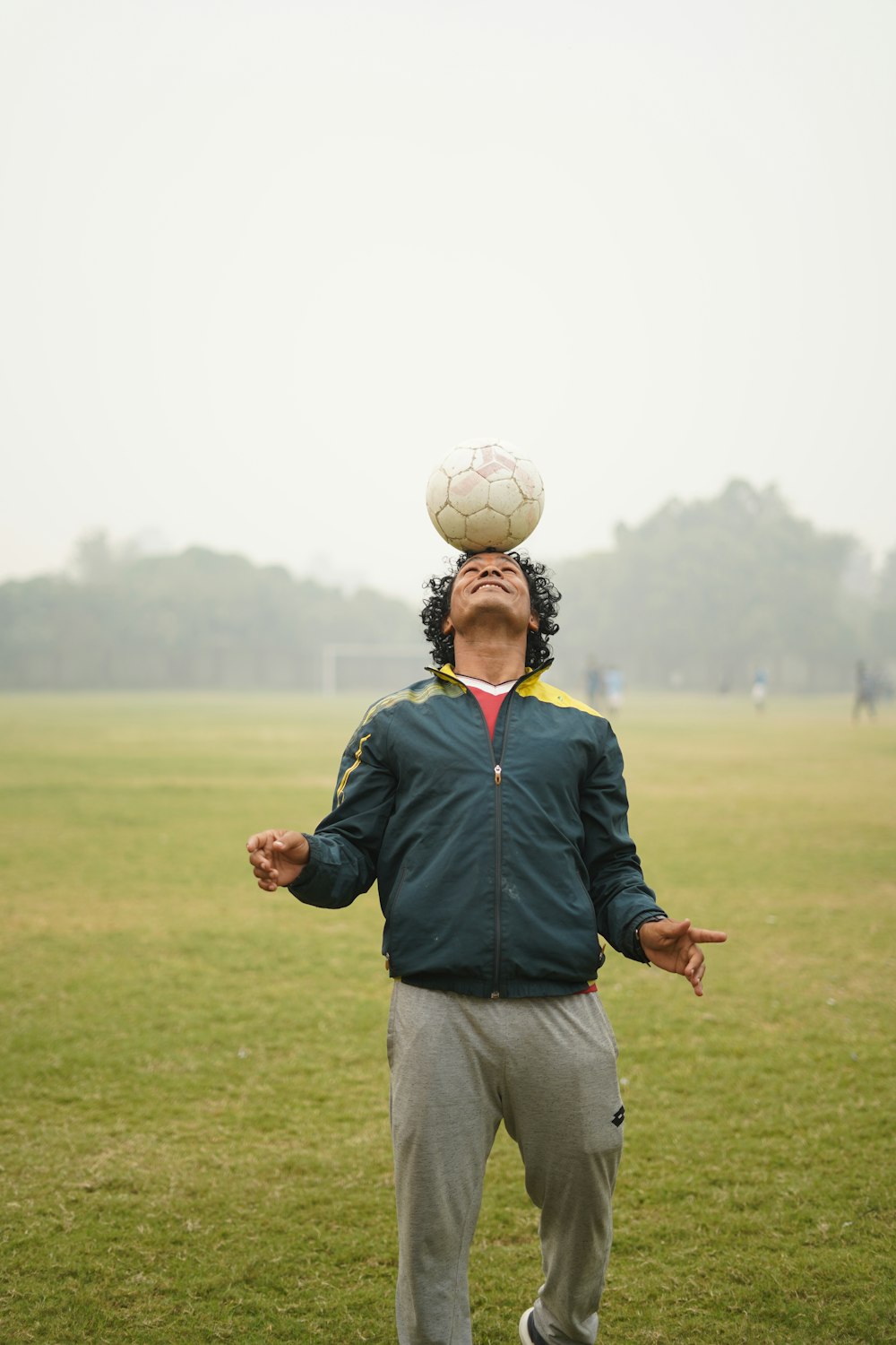man in blue jacket holding white soccer ball