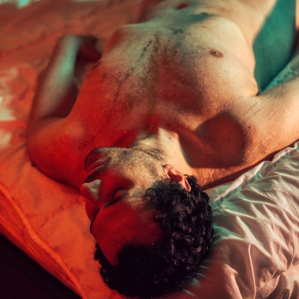 topless man lying on bed