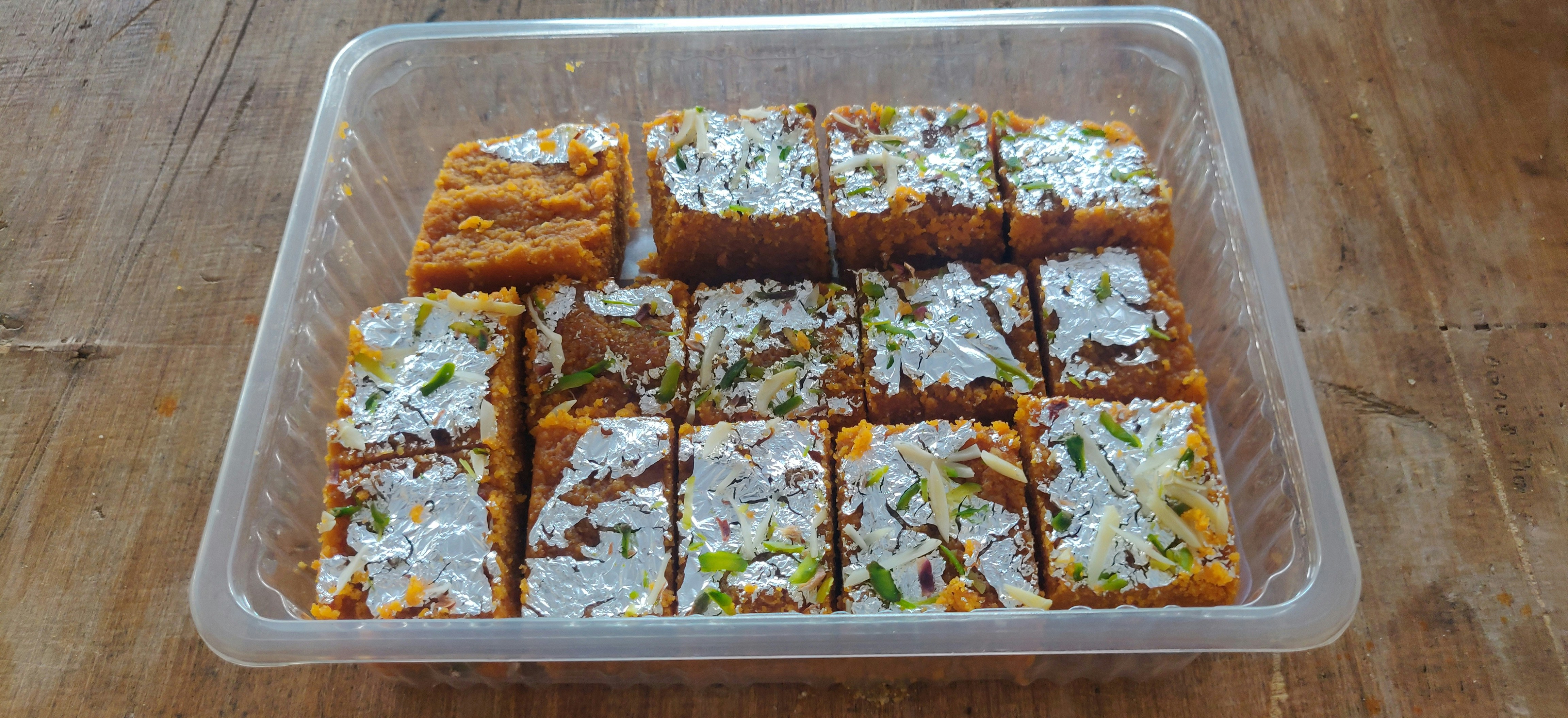 Close-up of premium golden Barfi with silver leaf on dark surface