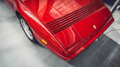 A shiny red sports car angled to highlight its curves, set on a smooth concrete floor.