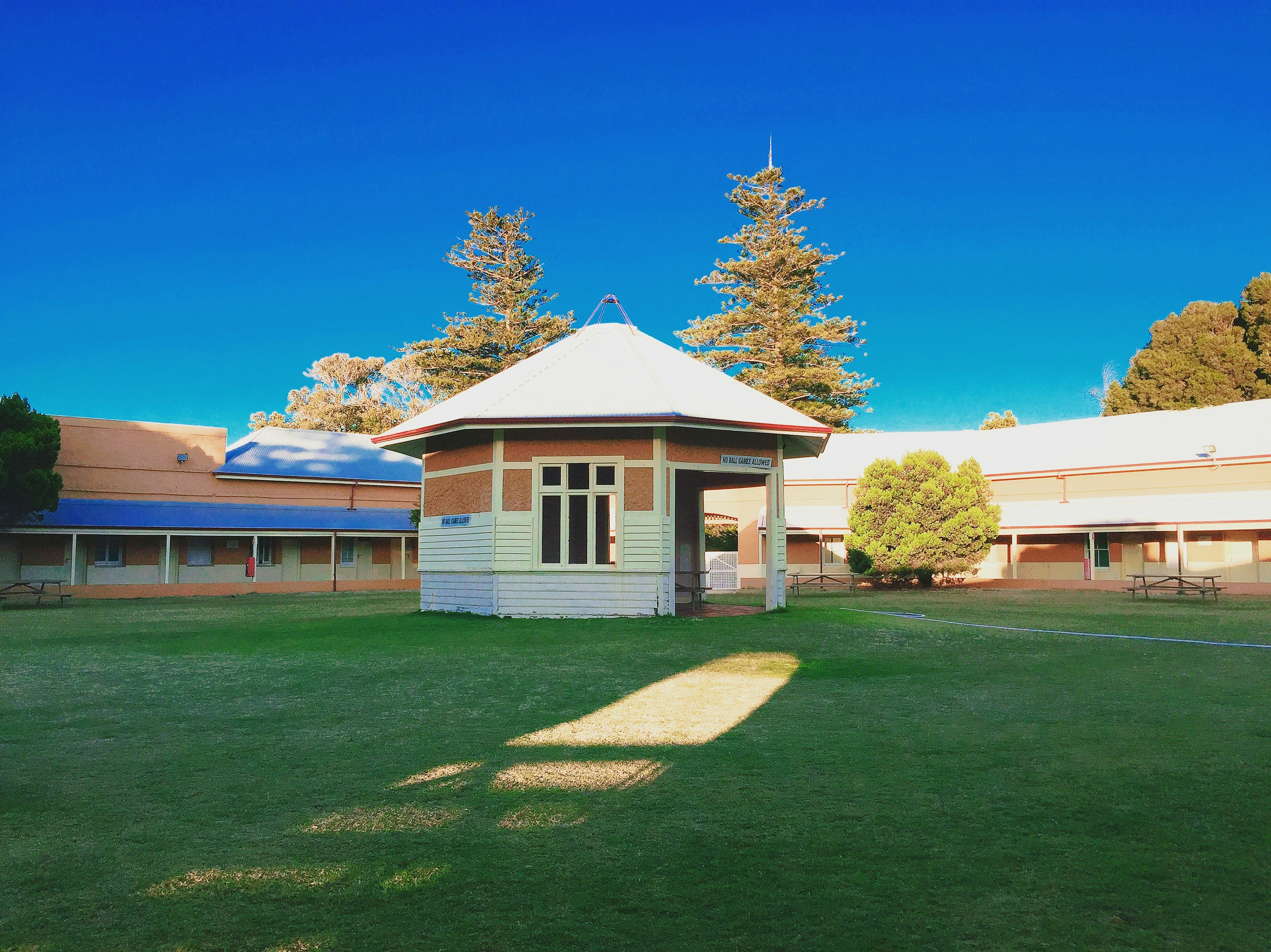 white and brown house near green grass field under blue sky during daytime