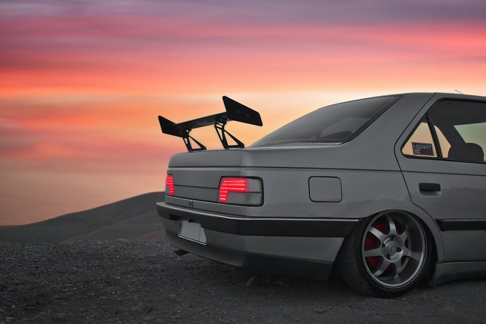 carro bmw preto na areia cinzenta durante o pôr do sol