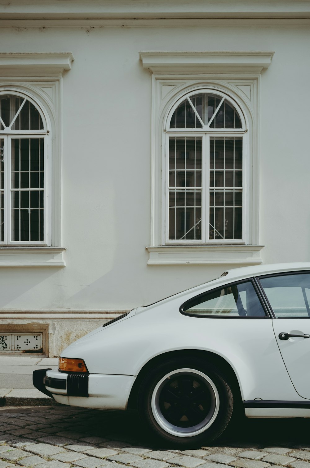 white car parked beside white concrete building