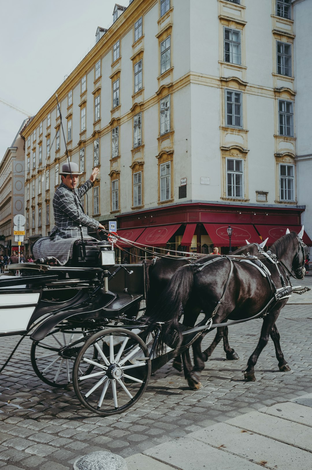 man riding on black horse carriage near beige concrete building during daytime