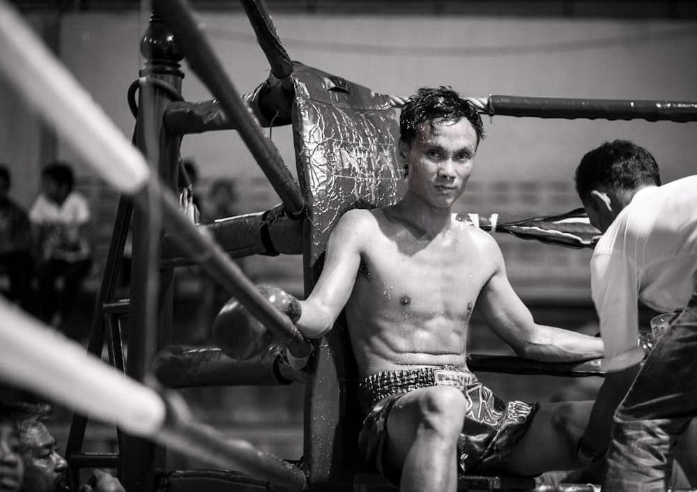 topless man in black and white shorts sitting on black metal frame