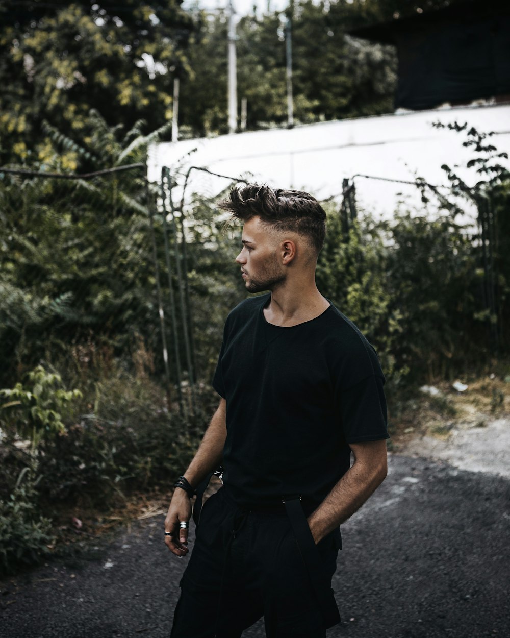 man in black crew neck t-shirt standing near green plants during daytime