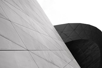 Complex geometric structures featuring a series of triangular patterns on curved and angled surfaces, highlighting modern architectural design.