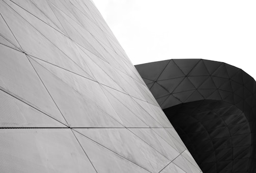 Complex geometric structures featuring a series of triangular patterns on curved and angled surfaces, highlighting modern architectural design.