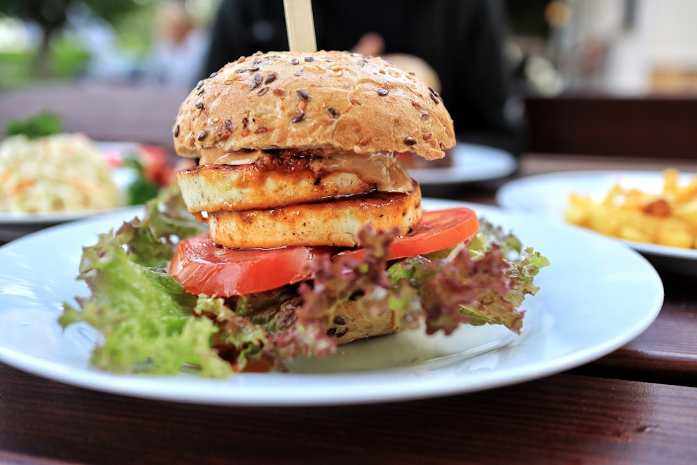 burger with tomato and lettuce on white ceramic plate